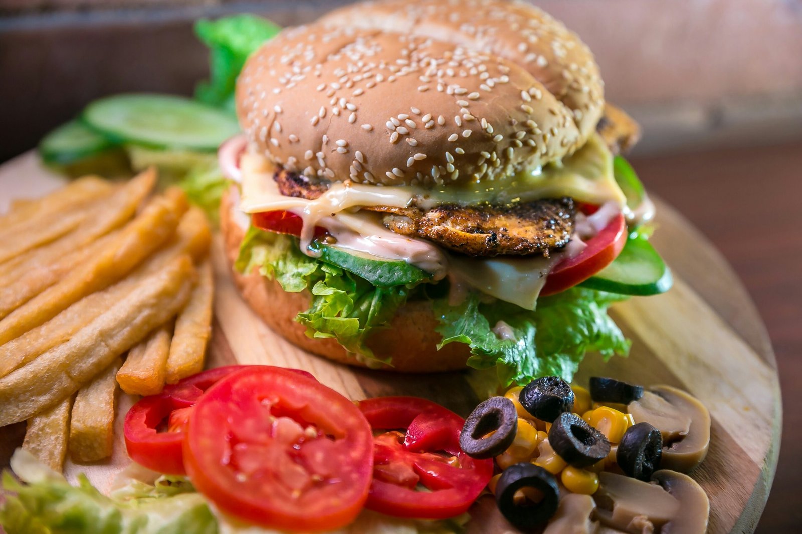 hamburger with vegetables and meat beside French fries